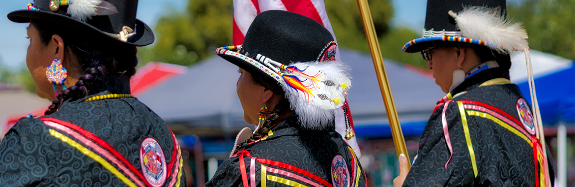 Three pow wow participants wearing decorated bowler hats